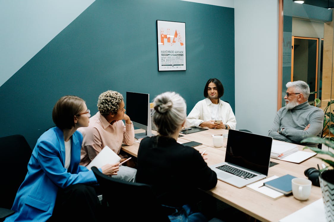 Deux collaborateurs en discussion encadrés par un manager dans un bureau
