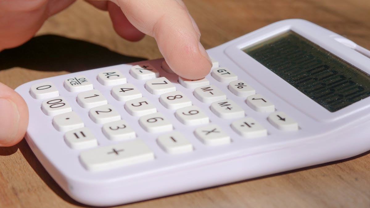 Calculatrice et documents financiers posés sur un bureau pour calculer la rentabilité d'une entreprise