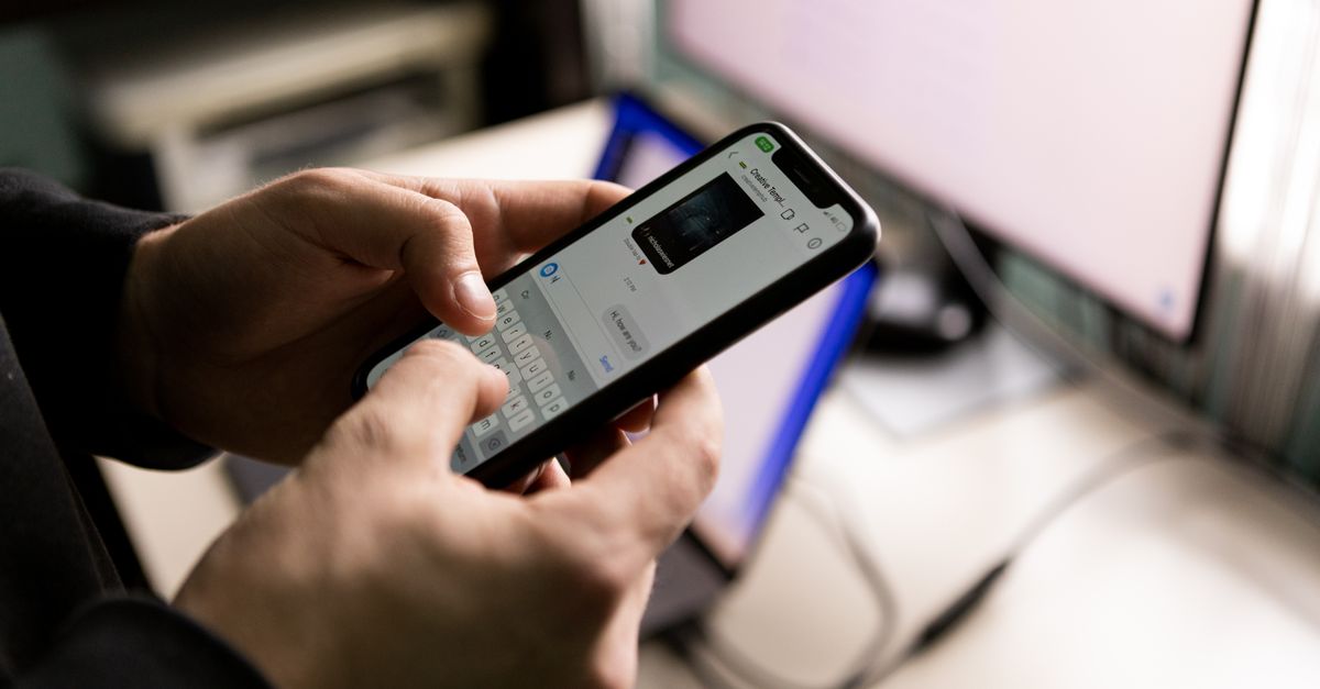 Personne tenant un smartphone avec une application de messagerie ouverte