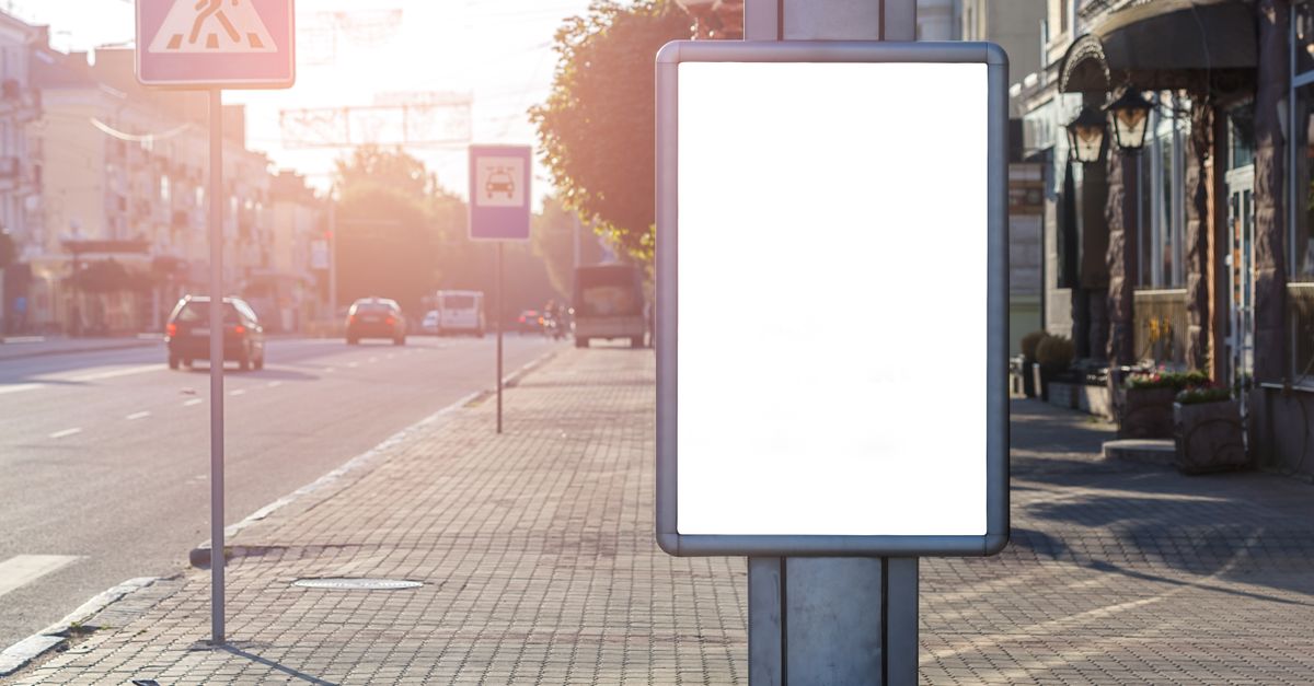 Panneau d'affichage publicitaire vierge dans une rue commerçante ensoleillée